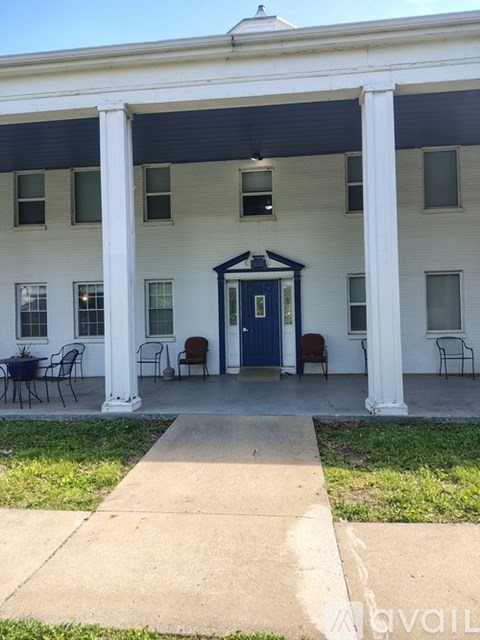 A white house with a blue door and a porch with chairs.