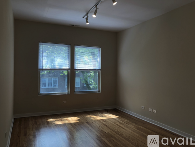 A room with wooden floors and two windows.