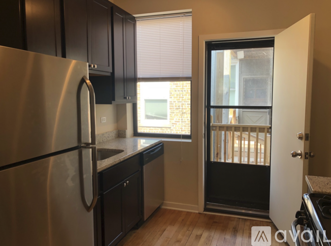 A kitchen with a stainless steel refrigerator and black cabinets.