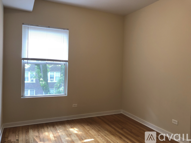 A room with wooden flooring and a window showing a view of a building outside.