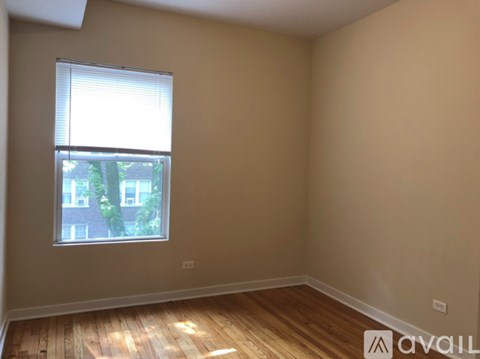 A room with wooden flooring and a window showing a view of a building outside.
