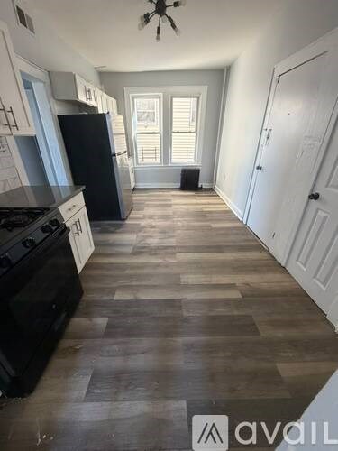 A kitchen with black appliances and wooden floors.