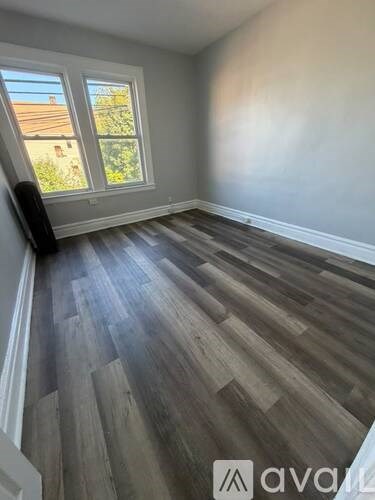 A room with wooden flooring and a window overlooking a garden.
