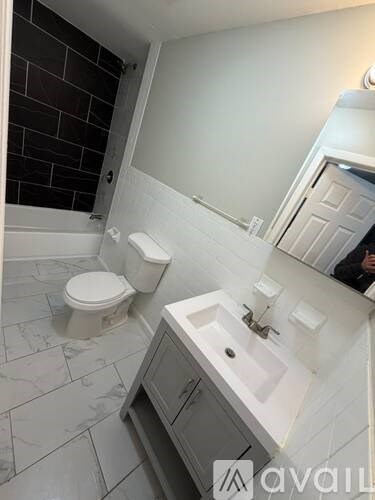 A bathroom with a toilet, sink, and mirror.