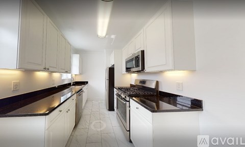 A kitchen with white cabinets and black countertops.
