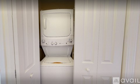A white washing machine is in a small space between two white doors.