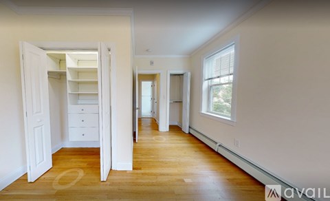 A room with wooden floors and white walls, with a doorway leading to another room.