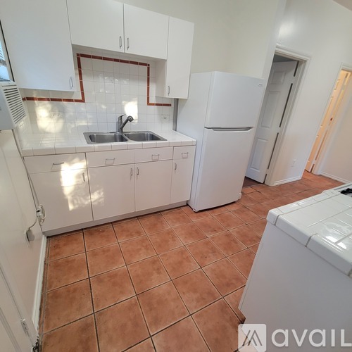A kitchen with white cabinets and a tiled floor.