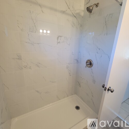 A bathroom with a marble tile wall and a tub.