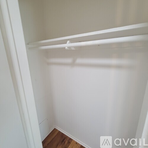 A white closet with a wooden floor and a white door.