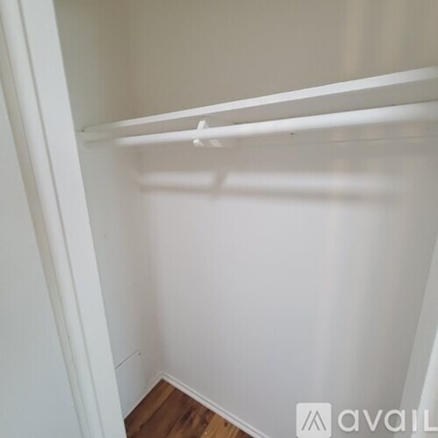 A white closet with a wooden floor and a white door.