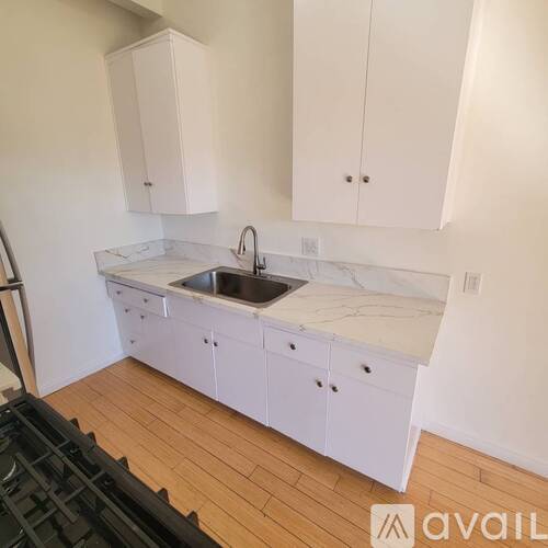 A kitchen with white cabinets and a marble countertop.
