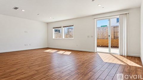 A spacious room with wooden flooring and white walls.