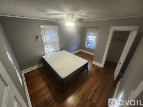 A bedroom with a bed, wooden floors, and a ceiling fan.