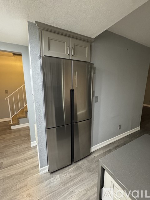 A stainless steel refrigerator with a freezer drawer and a bottom freezer compartment is in a kitchen.