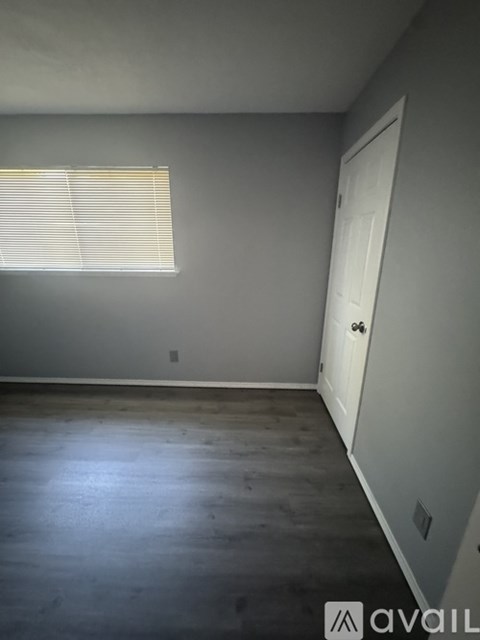 A room with a white door and a window with blinds.