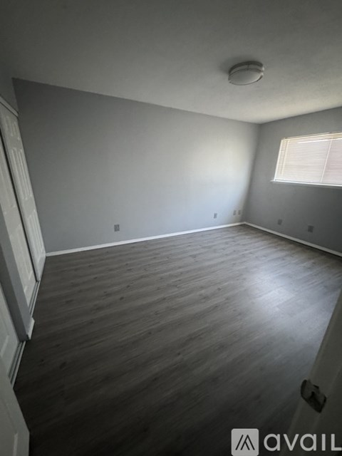 A room with wooden flooring and a window with blinds.