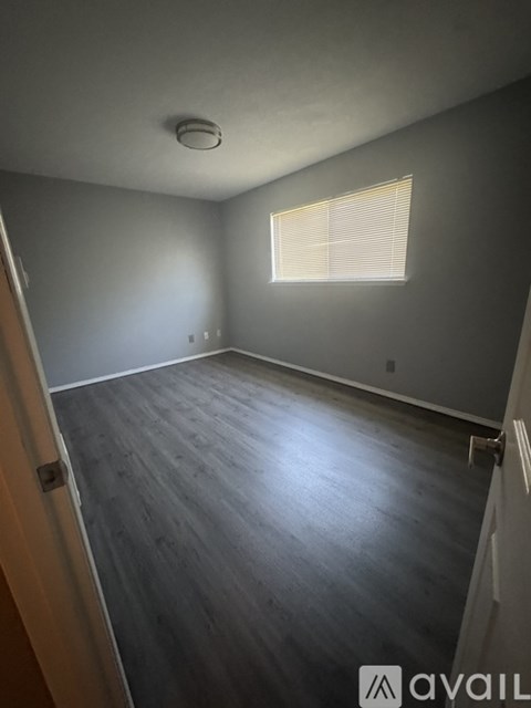 A room with wooden flooring and a window with blinds.