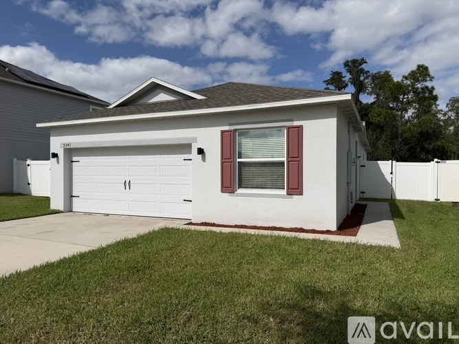 A white house with a red window trim and a garage door.