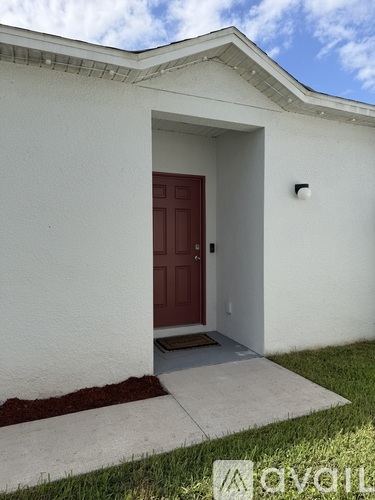 A white house with a red door and a small window above it.