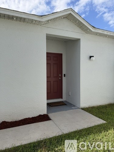 A white house with a red door and a small window above it.