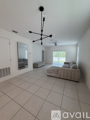 A spacious living room with a large sectional sofa and a chandelier hanging from the ceiling.