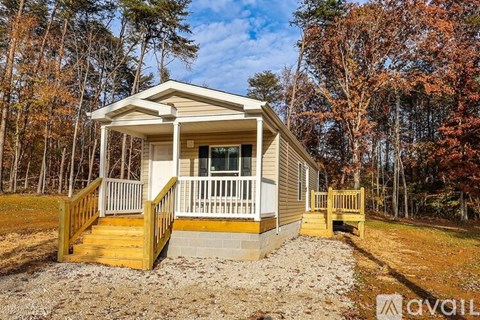 A small house with a porch is surrounded by trees.