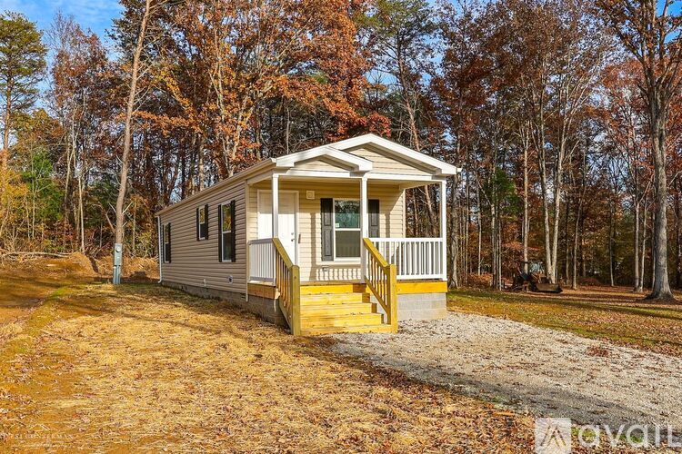 A small house with a porch is surrounded by trees.
