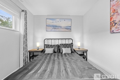 A bedroom with a large bed and a painting on the wall.