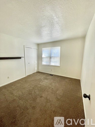 A room with a carpeted floor and a window showing a view of a building outside.