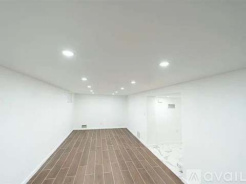 A spacious room with wooden flooring and white walls.