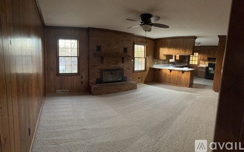 A living room with a fireplace and a ceiling fan.