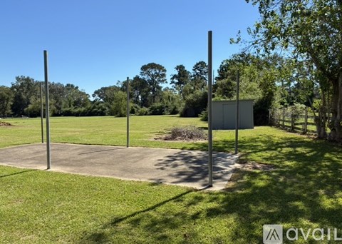 A grassy area with a concrete slab and four tall poles.