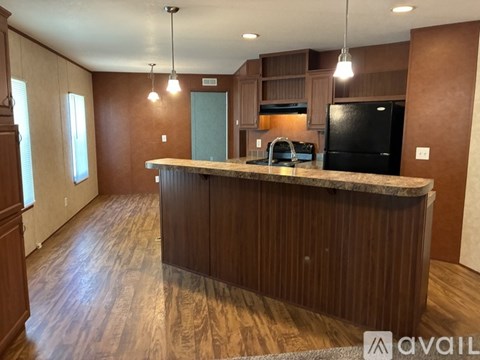A kitchen with a black fridge and wooden cabinets.