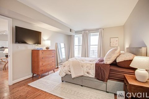 A bedroom with a large bed and a wooden dresser.