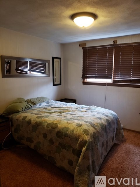 A bedroom with a bed and a window with blinds.