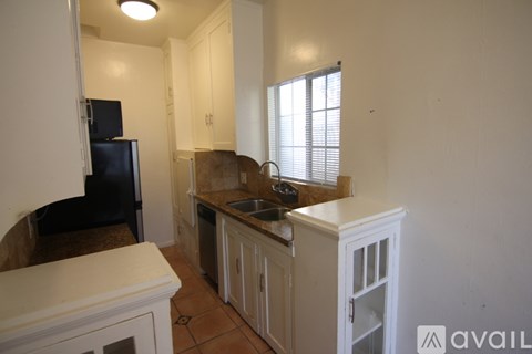 A kitchen with white cabinets and a black fridge.