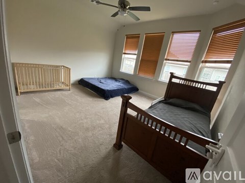 A bedroom with a bed, a crib, and a ceiling fan.