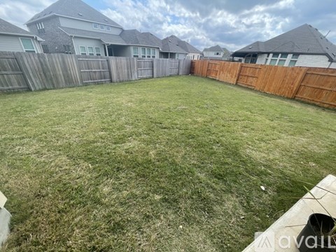 A backyard with a wooden fence and a grassy area.