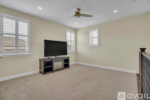 A living room with a television and a ceiling fan.