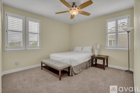 A bedroom with a bed, nightstand, and window with blinds.