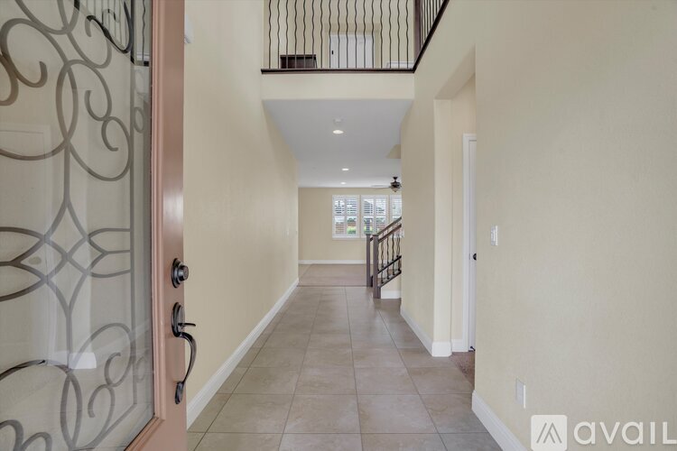 A hallway with a glass door and a balcony with a metal railing.