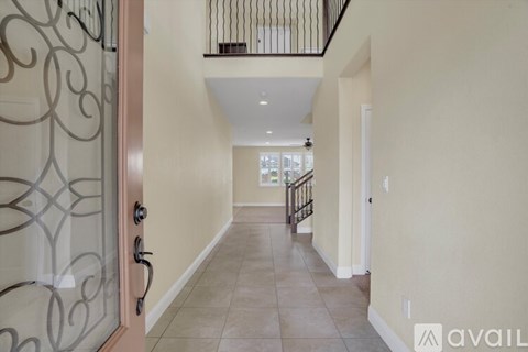 A hallway with a glass door and a balcony with a metal railing.