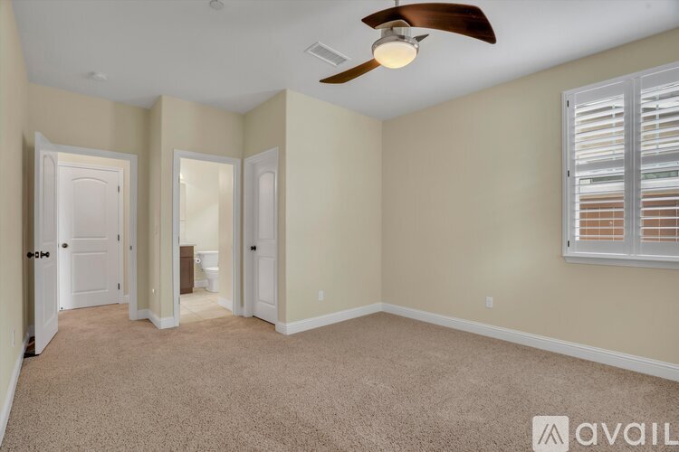 A room with a ceiling fan and carpeted floor.