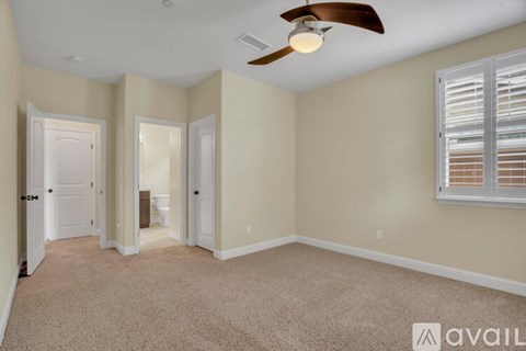 A room with a ceiling fan and carpeted floor.