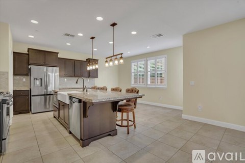 A kitchen with a refrigerator, sink, and a dining table with chairs.