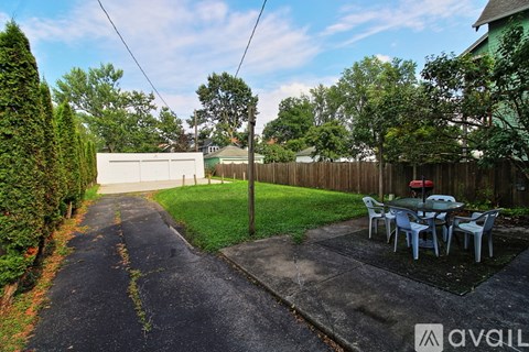 A backyard with a table and chairs is surrounded by a fence and trees.