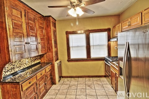 A kitchen with wooden cabinets and a black refrigerator.