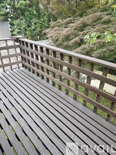 A wooden deck with a railing and trees in the background.