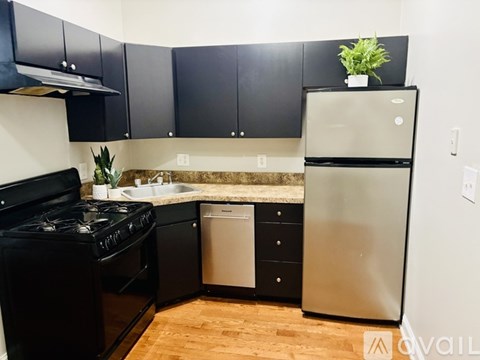 A kitchen with black cabinets and a stainless steel refrigerator.